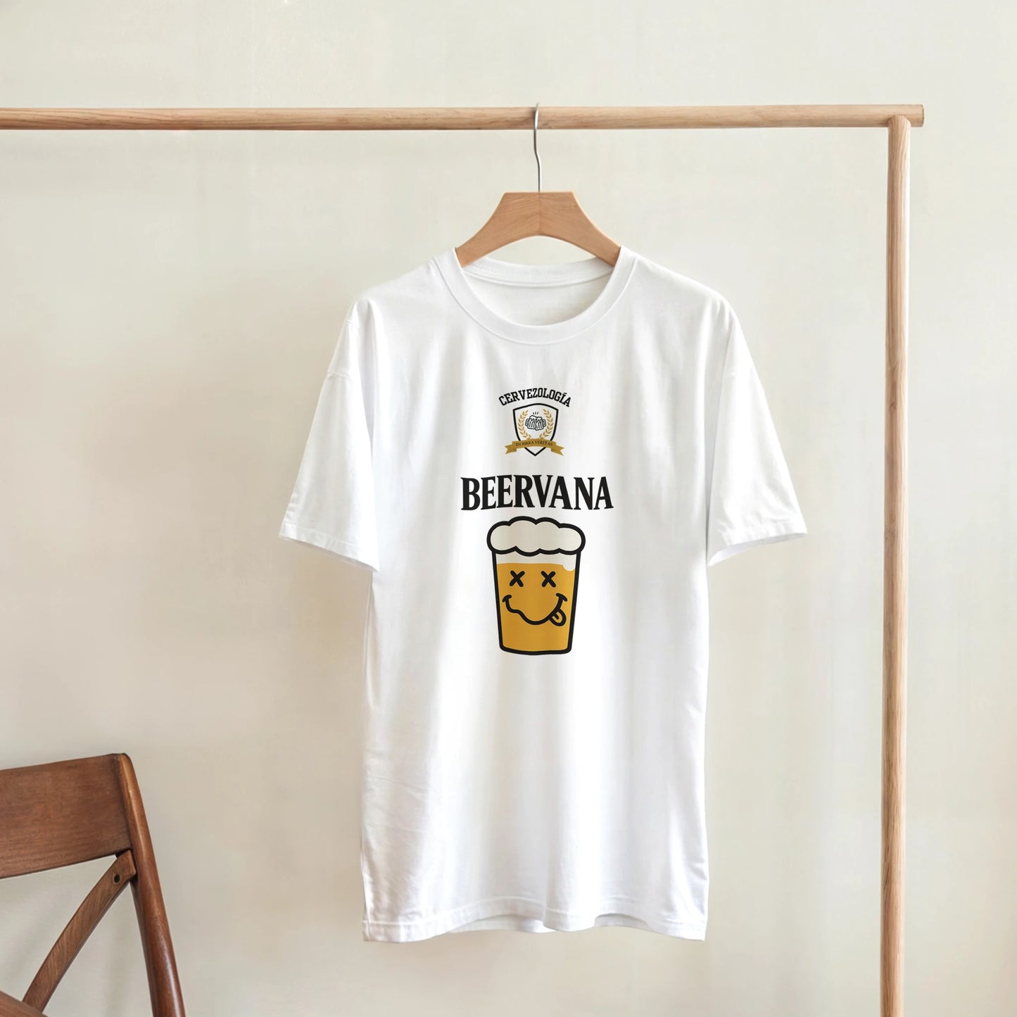 Camiseta blanca con estampado frontal de vaso de cerveza y texto, colgada en percha.