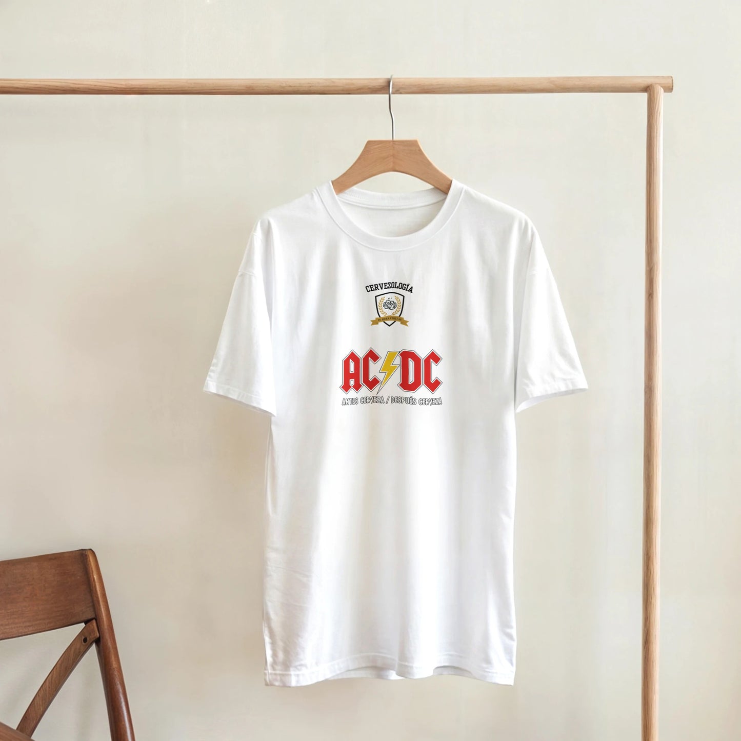 Camiseta blanca AC/DC con logo rojo y dorado, colgada en percha